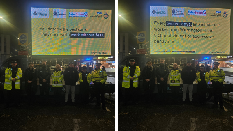 Police and ambulance workers standing outside on a street in front of a projector screen