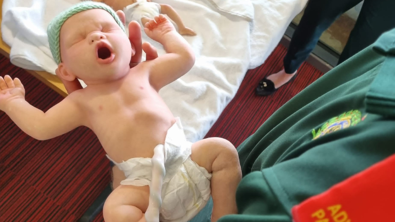 Maternity baby training dumy being held by ambulance clinician.