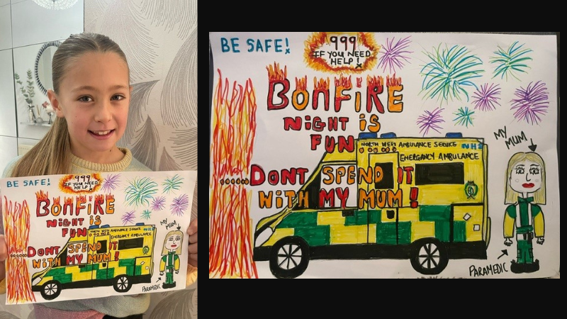 A child holding up a colorful poster with the message "Bonfire night is fun don't spend it with my mum," featuring drawings of fireworks, an ambulance, and a paramedic. The poster includes the emergency number "999" and a "Be Safe!" slogan.