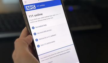 Hand holding a smartphone displaying the NHS 111 online webpage with options for medical help and services.